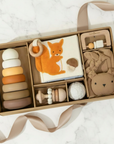Collection of baby toys in a box on a white marble surface