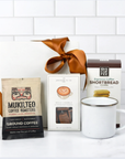Coffee package, mug, and cookies on a white surface with a white tiled wall background