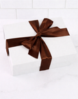 White gift box with a brown ribbon on a white background